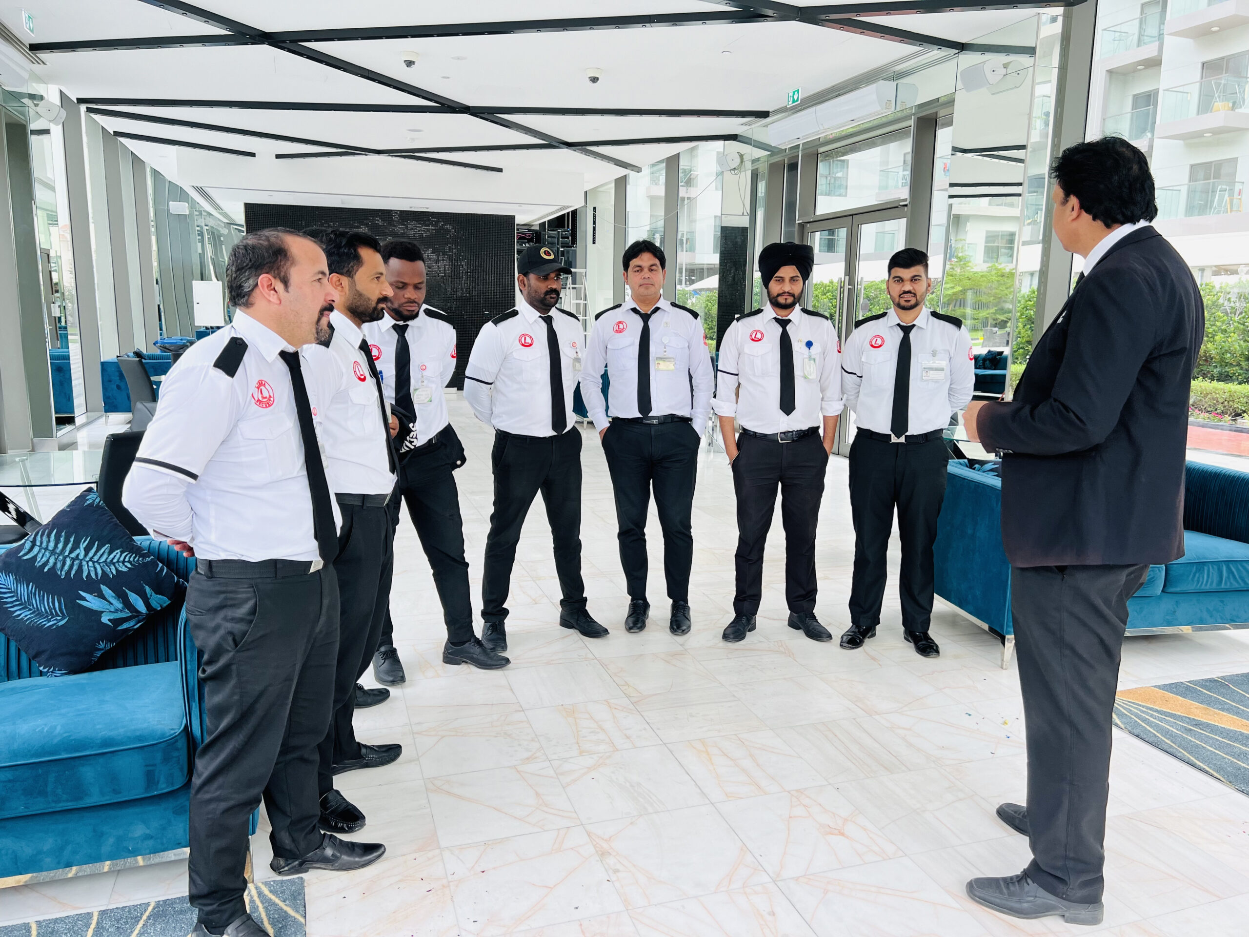 A team of uniformed security personnel receiving instructions from a supervisor inside a modern building, showcasing the professionalism and readiness of a leading security services company in Dubai.